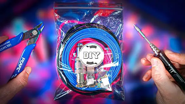 Eine versiegelte Plastiktüte mit der Aufschrift "DIY USB Cable Kit" enthält Kabel und elektronische Teile, die zwischen einem Drahtschneider und einem Lötkolben vor einem bunten, verschwommenen Hintergrund gehalten werden.