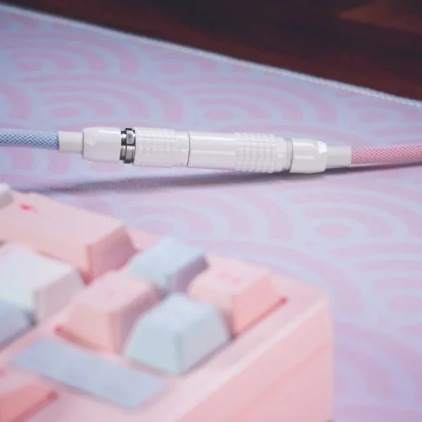 Close-up of a pastel mechanical keyboard with blue and pink keys, paired with a Custom Straight Keyboard Cable - Detachable featuring a white connector, and a soft purple wave-patterned mouse pad.