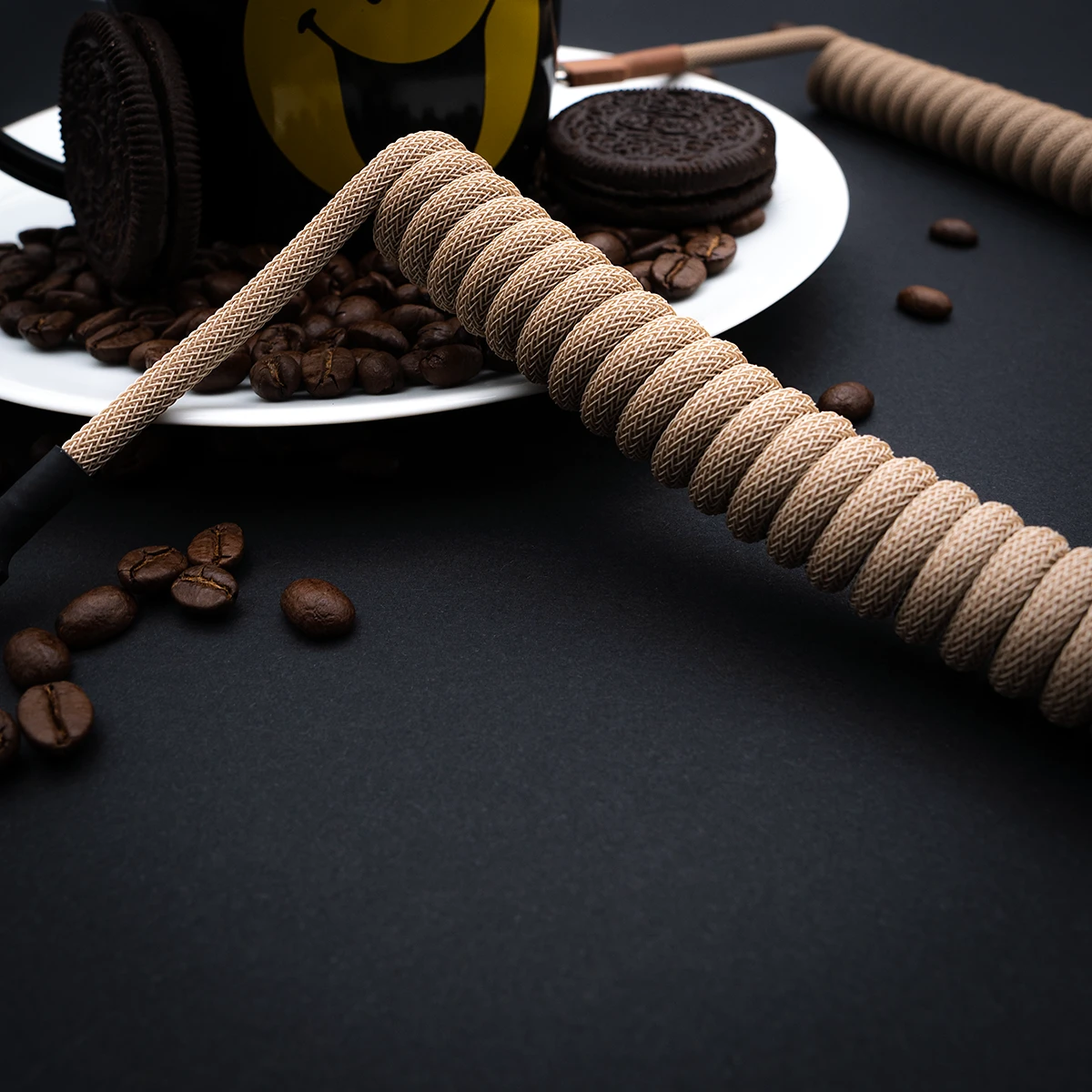 Beige Spiralkabel abgewinkelte Kaffeebohnen Beige gewickeltes Paracord-Tastaturkabel mit eleganter Oberfläche, mit abnehmbarem Stecker für eine einfache Anpassung, umgeben von Kaffeebohnen.