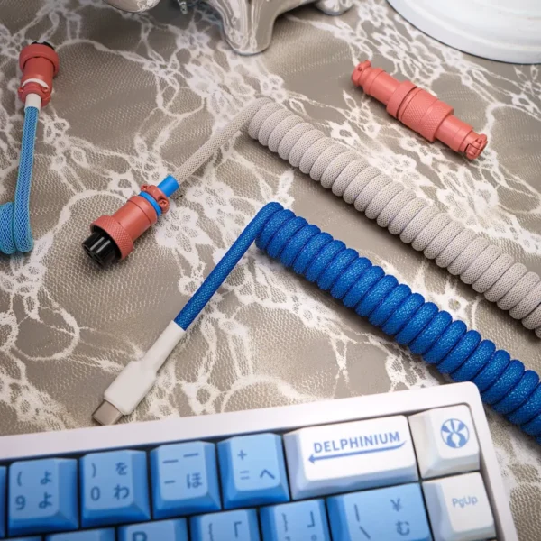 Blue beige coiled cables usb c top view A vibrant blue coiled keyboard cable features USB-C and aviator connectors, braided for durability. Perfect for custom setups, showcasing stylish textures.