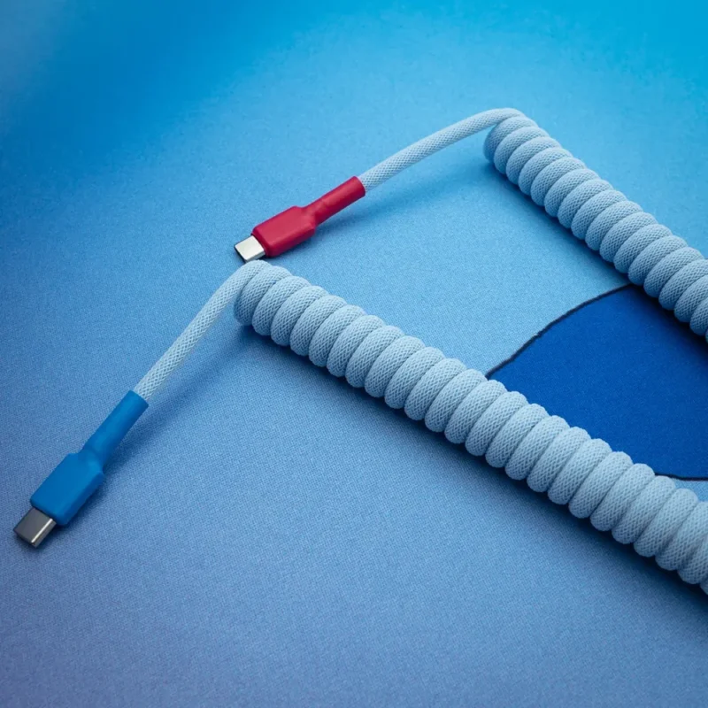 Câble USB-C spiralé bleu et rouge, vue de dessus Câble de clavier spiralé doté de connecteurs USB-C, avec une finition tressée bleu clair et des accents rouges ; conçu pour offrir durabilité et style dans les configurations personnalisées.