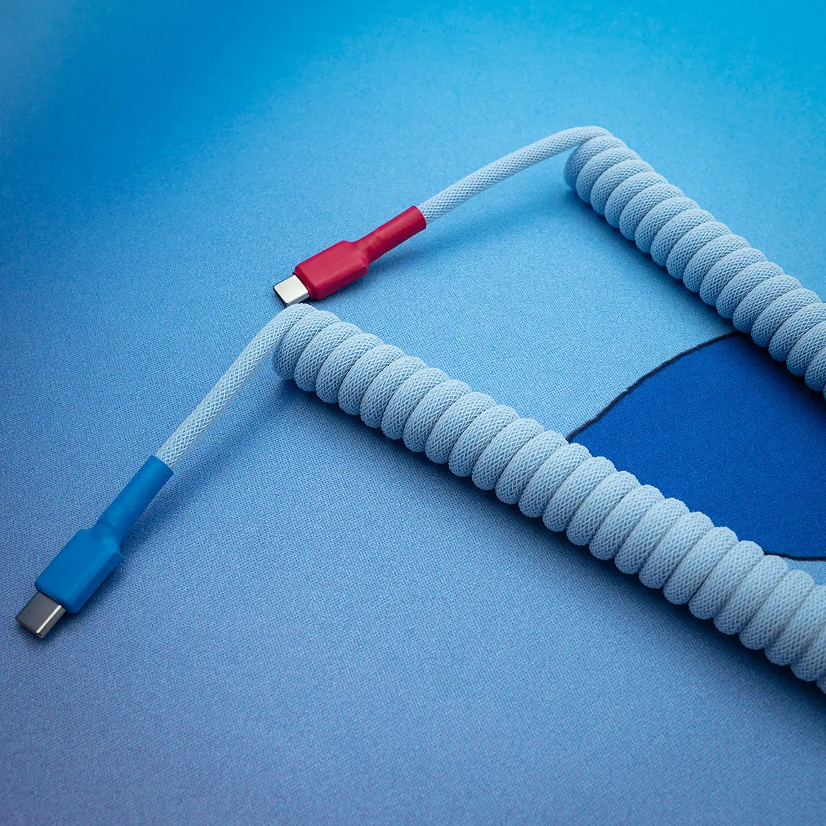Blau, rot, gewickeltes USB-C-Kabel, Draufsicht Spiralkabel für die Tastatur mit USB-C-Anschlüssen, geflochtenem hellblauem Finish und roten Akzenten; Entwickelt für Langlebigkeit und Stil in benutzerdefinierten Setups.