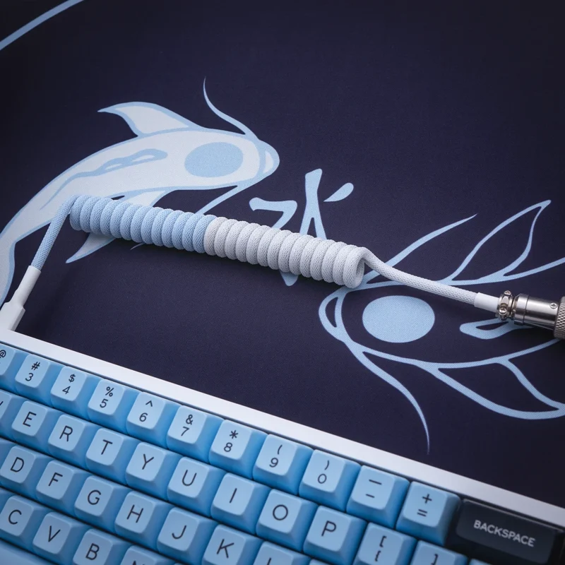 Blue white coiled cable angled koi mat Coiled keyboard cable in blue and white paracord, featuring detachable connectors and high-quality metal housing, showcasing a sleek, textured finish.