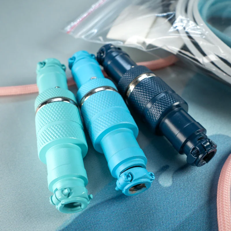 Cerakoted gx16 4 pins connectors blue cyan dark blue Three metal gx16 4 pins aviators connectors with a Cerakote finish in different shades of blue are arranged side by side on a light blue surface.