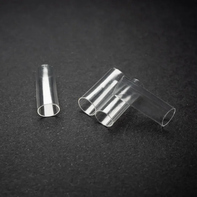 Clear heatshrink 6 5mm 1 4 Four Clear Heatshrink (6.5mm) – (1/4) transparent plastic tubes are lying on a black surface, with three grouped together and one separated to the left.