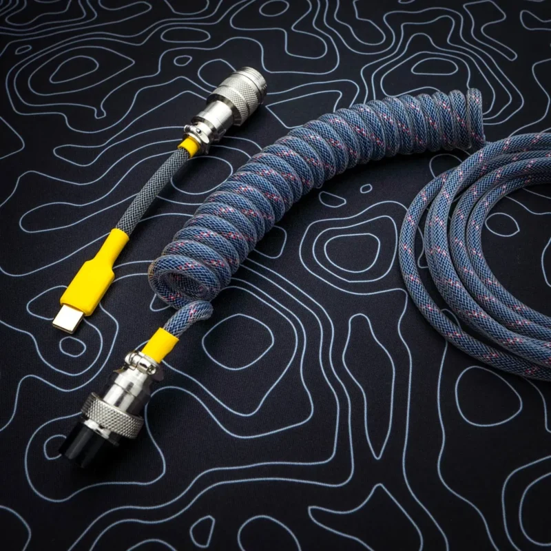 Dark blue coiled cable overhead usb c A dark blue coiled keyboard cable featuring a USB-C connector with a yellow accent