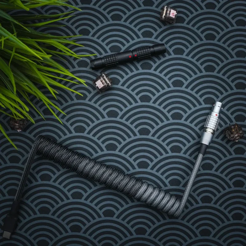 Dark gray coiled keyboard cable with a sleek, braided texture. Features USB-C connectors, detachable metal AVIATOR plug, and high-quality heatshrink.