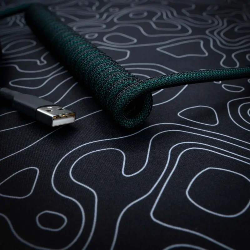 Dark green coiled usb cable angled view A stylish green coiled keyboard cable with a braided finish, featuring a USB connector, ideal for custom setups and high-quality connectivity.