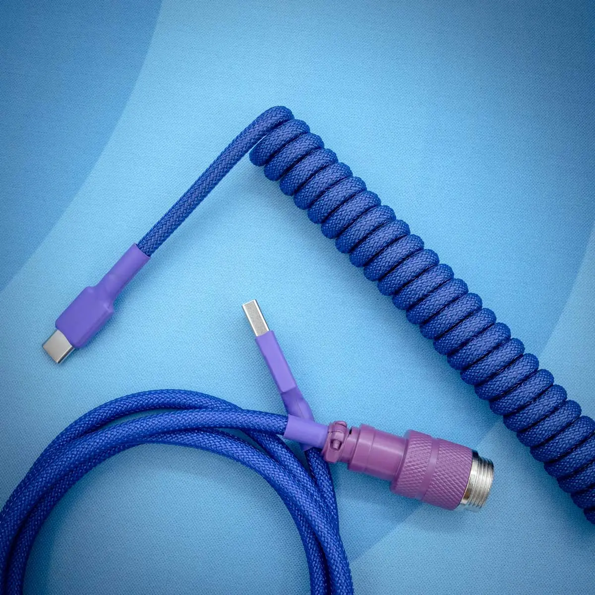 Dark purple coiled cable usb c top view 1 Dark purple, coiled keyboard cable with USB-C and detachable aviator connectors. Features durable paracord, smooth braiding, and quality finish.