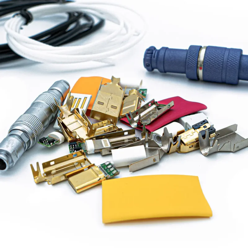 Diy usb kit components Assorted electronic and metal connector parts, various electronic components, and connectors in a plastic bag, including three colored wires, are arranged on a white surface.