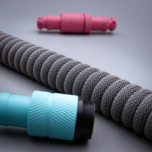 Gray coiled cable pink blue connectors Custom keyboard cable featuring a textured gray coil, with turquoise and pink detachable connectors, ideal for versatile setups. Quality braiding ensures durability.