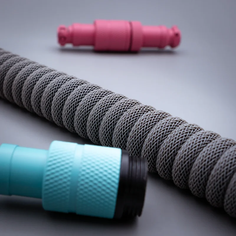 Graues Spiralkabel rosa blaue Steckverbinder Spezielles Tastaturkabel mit einer strukturierten grauen Spule und abnehmbaren Türkis- und Rosasteckern, ideal für vielseitige Setups. Hochwertiges Geflecht sorgt für Langlebigkeit.