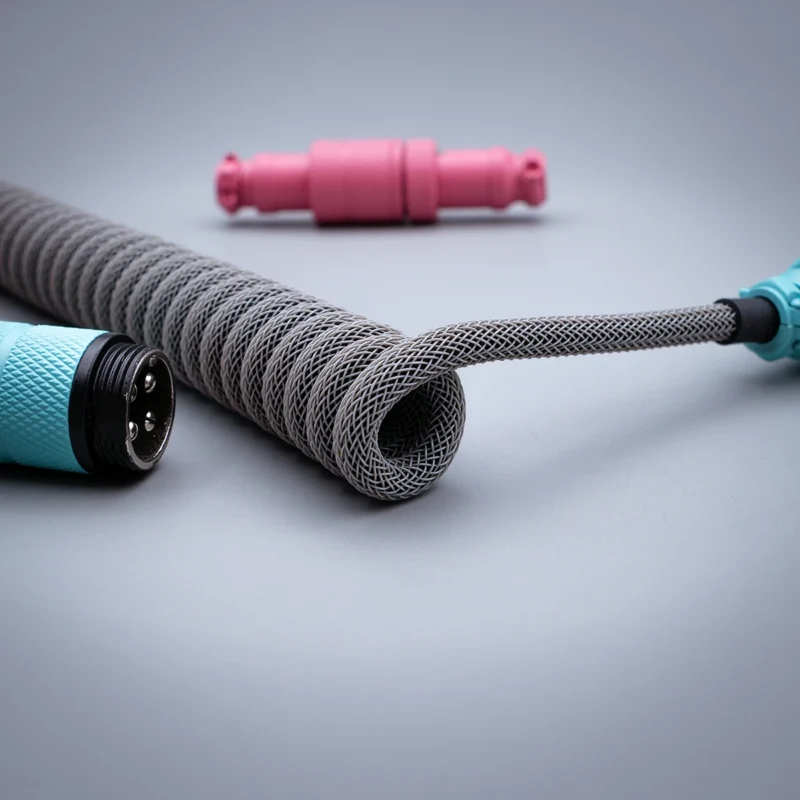 Gray coiled cable usb c pink blue connectors Coiled custom keyboard cable featuring high-quality braid in gray, detachable USB-C and aviator connectors, accented with vibrant pink and teal housing.