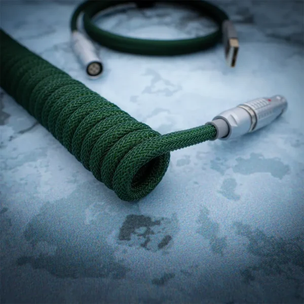 Green coiled cable lemo style angled view Custom green paracord keyboard cable features a coiled design, USB Type-A and aviator connectors, with high-quality heatshrink and durable braiding.