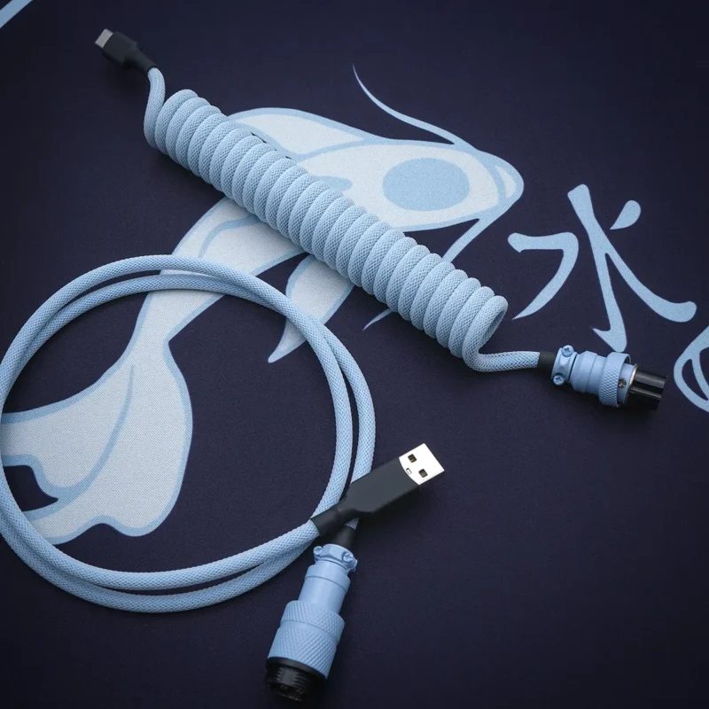 Hellblaues Spiralkabel USB Schrägansicht Blaues GMK Mizu-Tastaturkabel mit spiralförmigem Design, USB-C-Stecker, abnehmbarem Pilotenstecker und strukturiertem Paracord-Finish für Langlebigkeit und Stil.