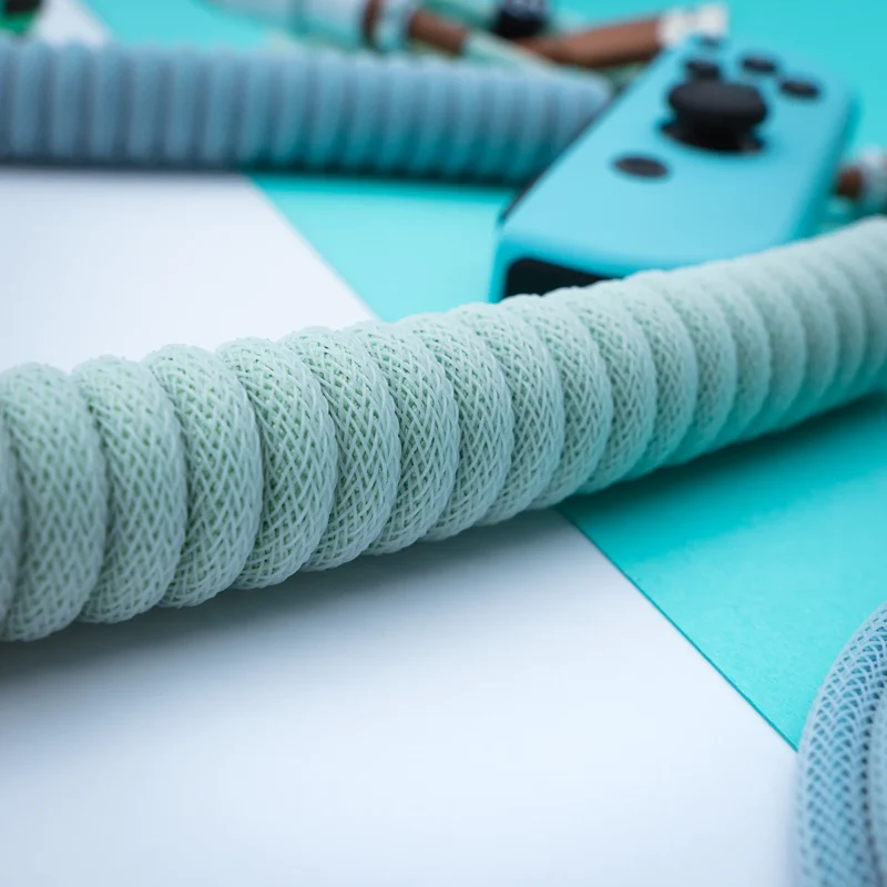 Mint coil cable closeup usb c perspective Coiled PBT Islander Keyboard Cable showcases a mint green paracord finish, featuring high-quality braiding and detachable connectors, ideal for custom setups.
