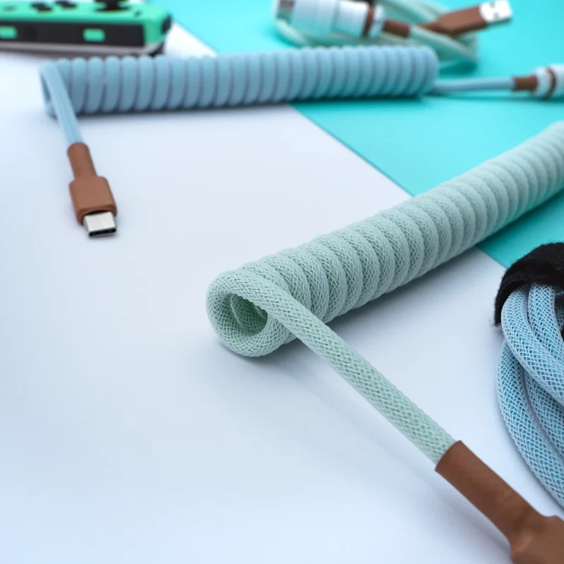 Mint coiled usb c cable angled view Curled mint green coil cable with a USB-C connector. Features a durable paracord finish, ensuring flexibility and style for custom keyboard setups.