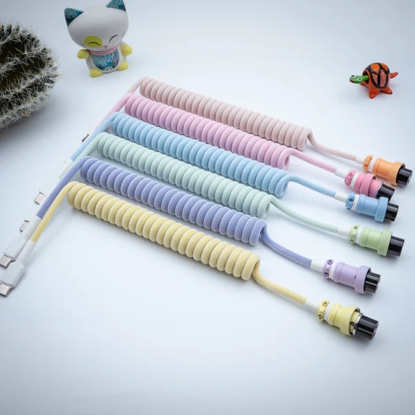 Pastel coiled cables overhead gx16 connectors A vibrant collection of coiled keyboard cables featuring USB-C and aviator connectors, highlighted by colorful paracord braiding and quality finishes.