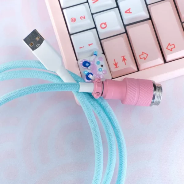 A vibrant blue coil keyboard cable featuring detachable pink metal connectors, a white USB end, and textured braiding for a premium finish.