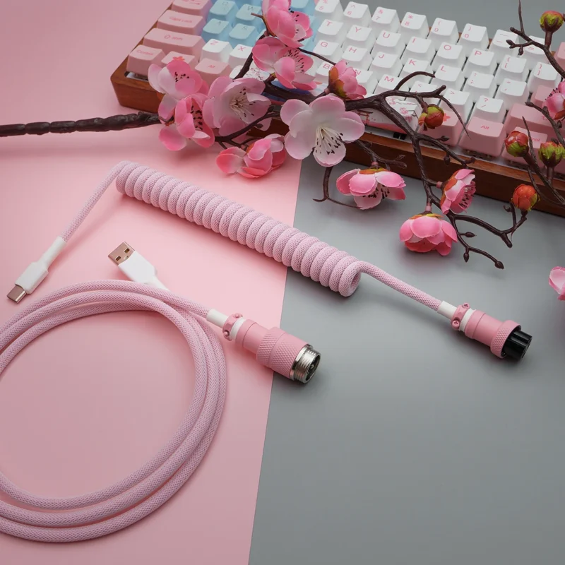 Pink coiled cable usb c aviator overhead shot Coiled pink paracord keyboard cable with USB-C and aviator connectors, featuring quality braiding, detachable plugs, and stylish heatshrink details.
