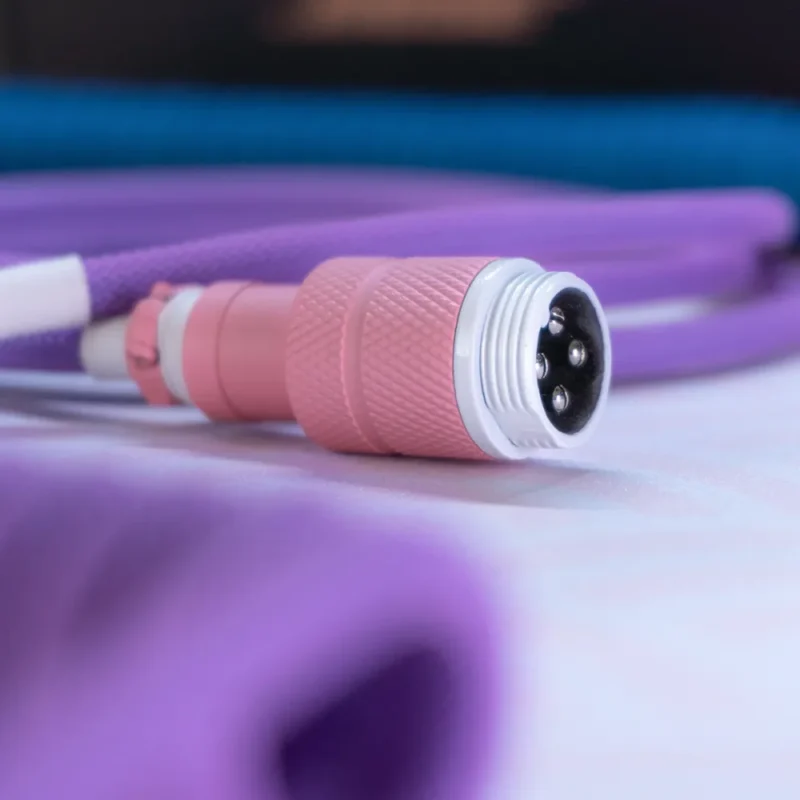 Connecteur rose câble violet gros plan angle Gros plan sur le câble pour clavier KAM Li'l Dragon, doté d'un connecteur aviateur rose texturé, d'un cordon paracord violet vif et d'une finition durable pour des configurations personnalisées de haute qualité.