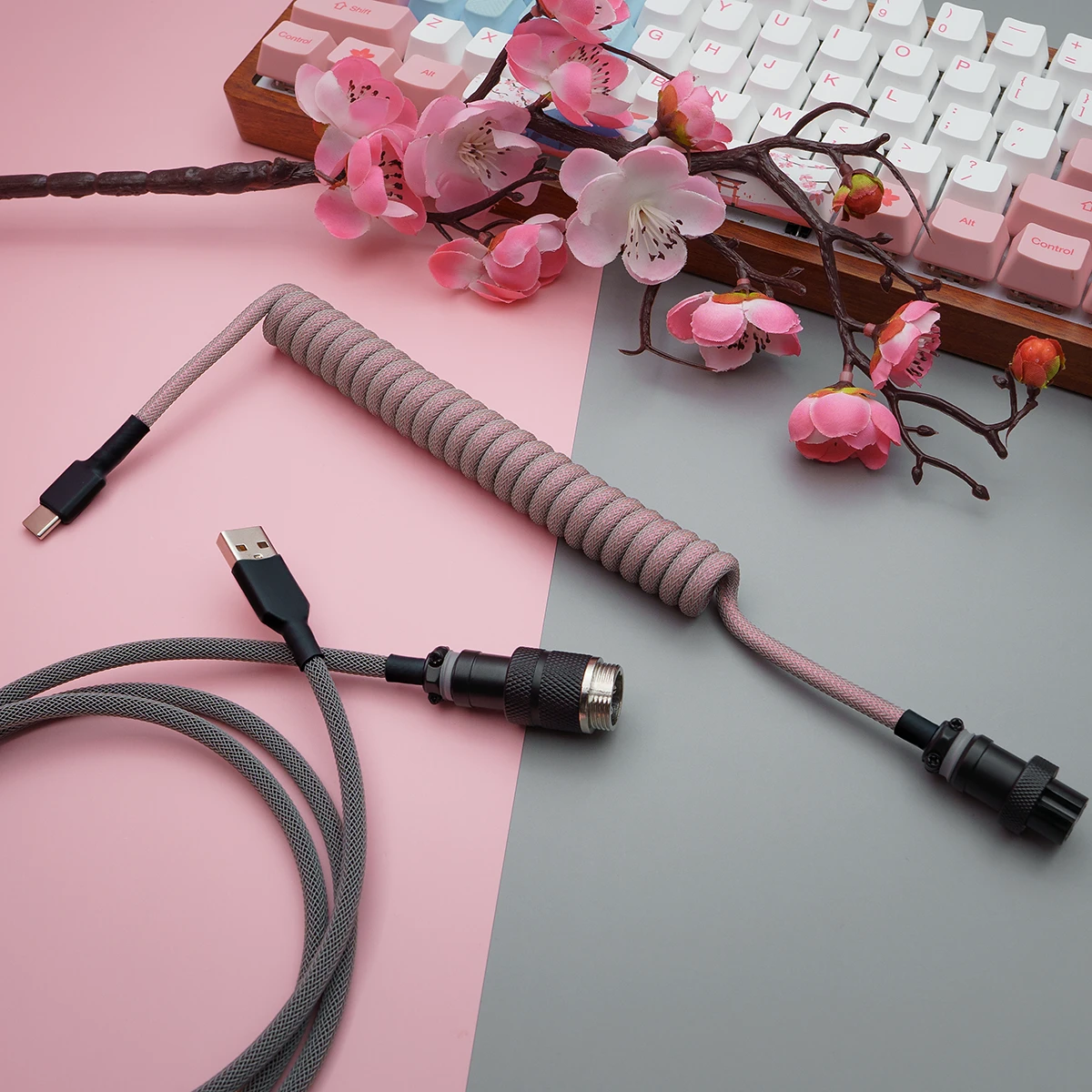 Pink gray coiled cable overhead gx16 connector Coiled pink paracord keyboard cable with USB-C and aviator connectors. Features quality braiding and detachable plugs for flexibility and style.