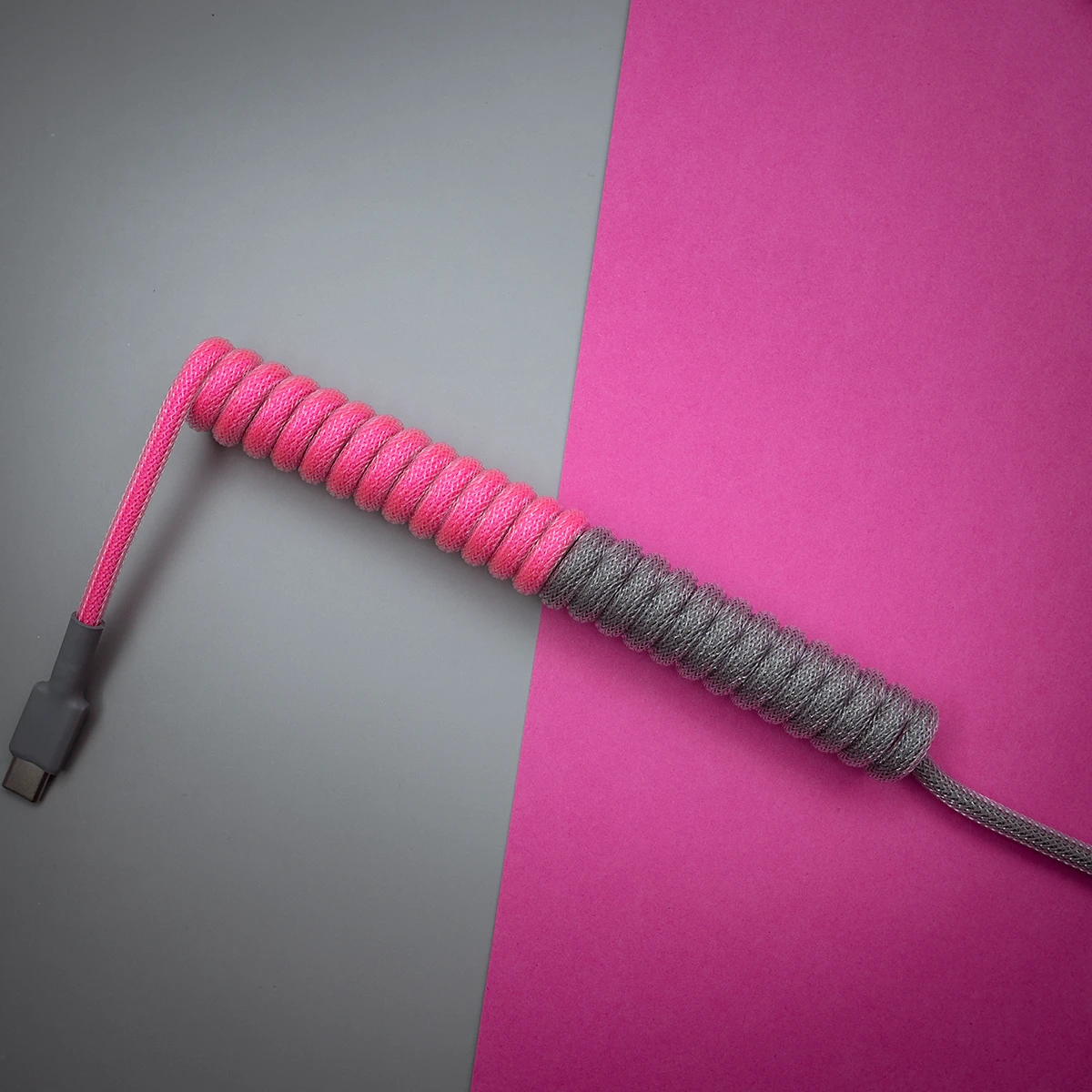 Pink gray coiled cable usb c top view Custom GMK 80082 keyboard cable features a vibrant pink and gray coiled design, USB-C connector, high-quality braiding, and durable heatshrink for maximum flexibility.