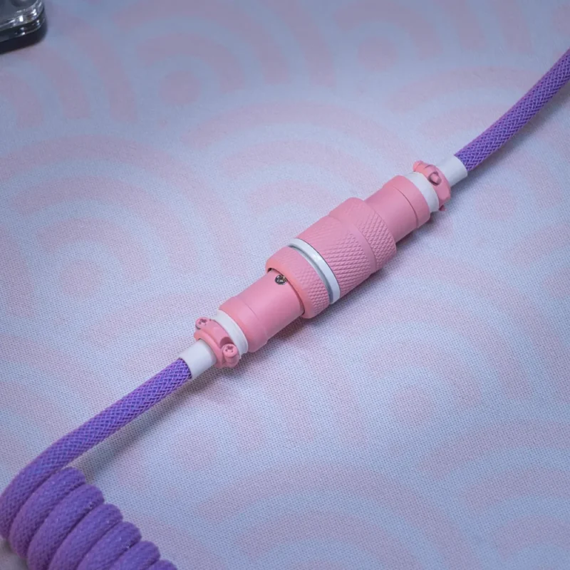 Gros plan sur un connecteur aviateur violet rose Câble de clavier spiralé avec un design paracord violet vif, un connecteur USB-C détachable et un boîtier métallique CNC rose élégant avec une finition texturée.