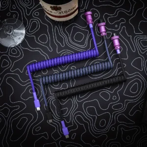 Purple black coiled cables top view aviator Three custom keyboard cables displayed on a textured background: one purple coiled