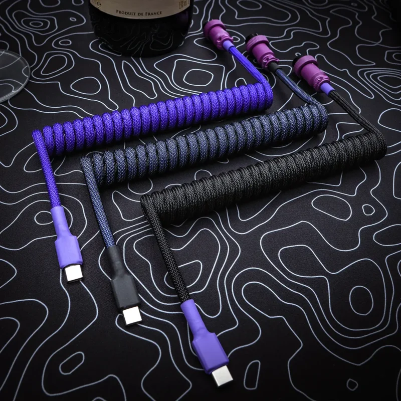 Lila schwarz Spiralkabel usb c Draufsicht Benutzerdefinierte Tastaturkabel mit Spulen in lila und schwarzem Paracord, USB-C-Anschlüssen und schlanken, abnehmbaren Steckern, die auf Stil und Langlebigkeit ausgelegt sind.