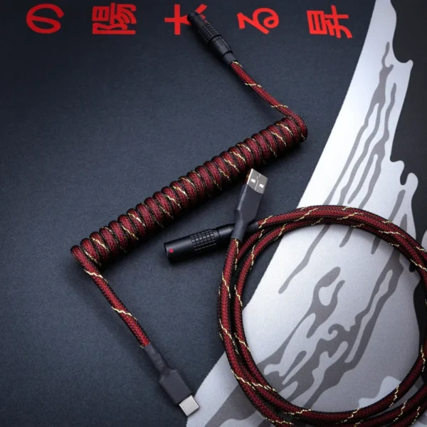 Red black coiled usb c cable overhead shot Custom keyboard cable featuring a coiled design with rich red and gold paracord finish
