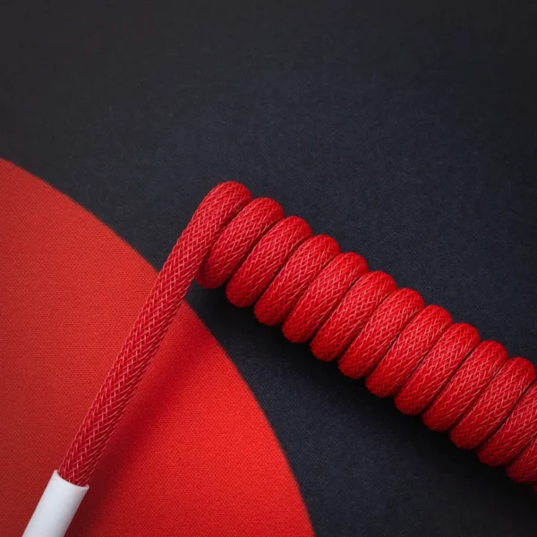 Coiled red paracord keyboard cable features a smooth finish, detaches via an aviator connector, and offers an eye-catching, vibrant design perfect for custom setups.