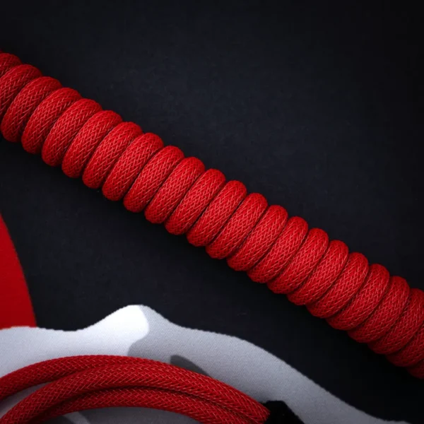 Coiled red paracord keyboard cable with a smooth finish, featuring a thick texture and quality braiding for durability, perfect for custom setups.