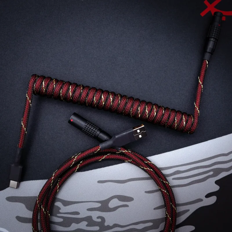 Red gold coiled cable usb c top view Coiled GMK Red Samurai Keyboard Cable with textured red and black paracord. Features USB-C, detachable aviator connectors, and high-quality braiding.