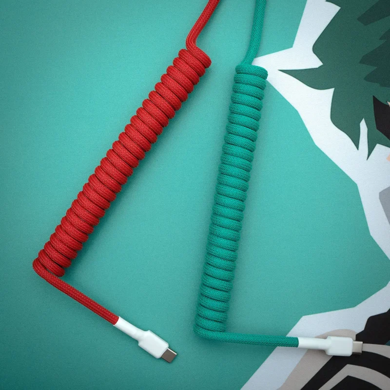 Rot Grün Spiralkabel USB C Draufsicht Zwei benutzerdefinierte Tastaturkabel in Rot und Grün mit gewickelten Abschnitten und USB-C-Anschlüssen, die hochwertige Flecht- und Verarbeitungsdetails aufweisen.