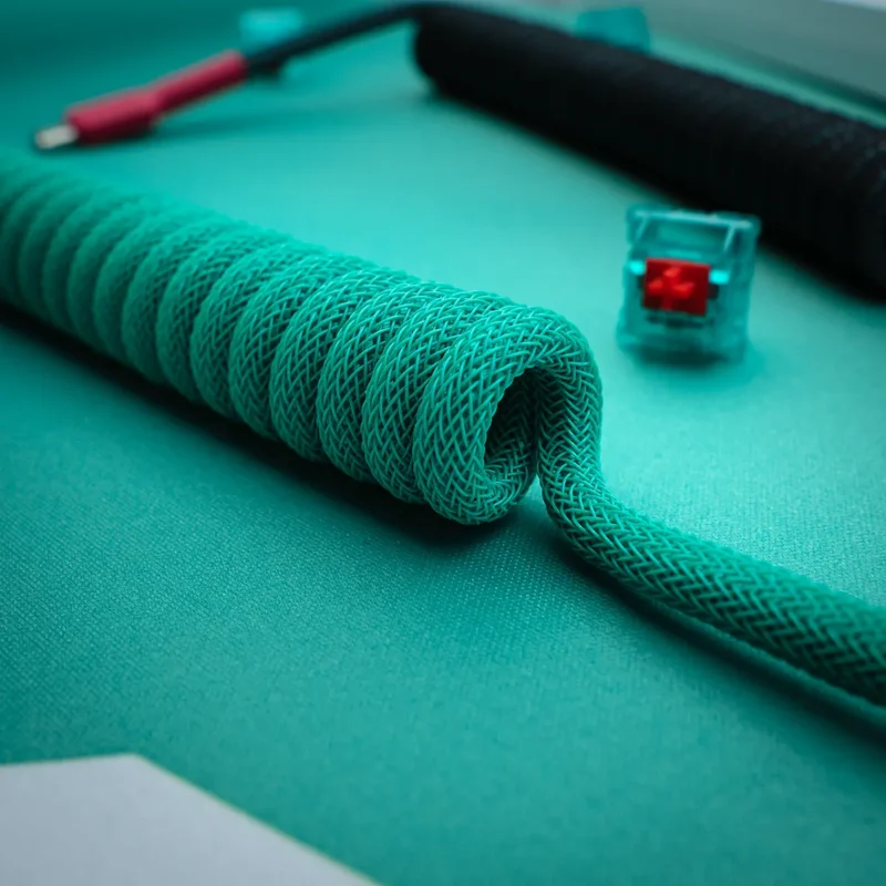 Teal coiled cable angled usb c closeup Coiled custom keyboard cable in vibrant teal, featuring sleek braiding, a straight section, and detachable connectors. Ideal for enhancing your setup.