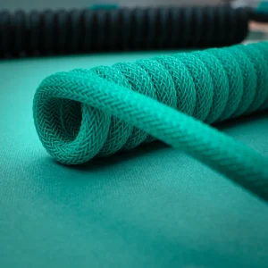 Teal coiled cable closeup textured sleeve A vibrant teal coiled keyboard cable showcasing intricate braiding and a smooth finish, ideal for custom setups, emphasizing style and durability.