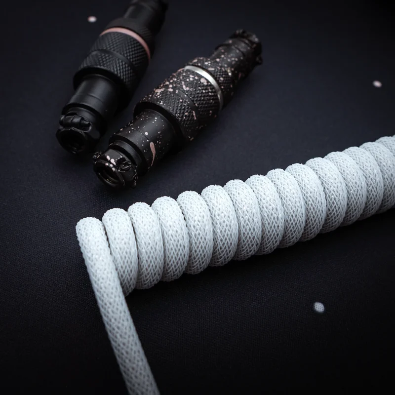 Weißes Spiralkabel schwarze Stecker Nahaufnahme Aufgewickeltes weißes Paracord-Tastaturkabel mit strukturierten Anschlüssen in schwarzen und rosa Akzenten. Verfügt über ausziehbare Abschnitte und abnehmbare Stecker für Vielseitigkeit.